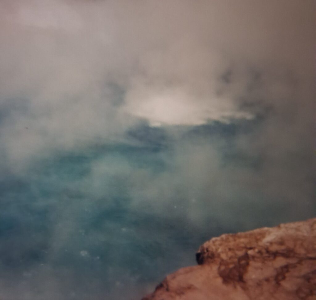 Geothermal pool in Yellowstone National Park showing vivid blue water and steam vents
